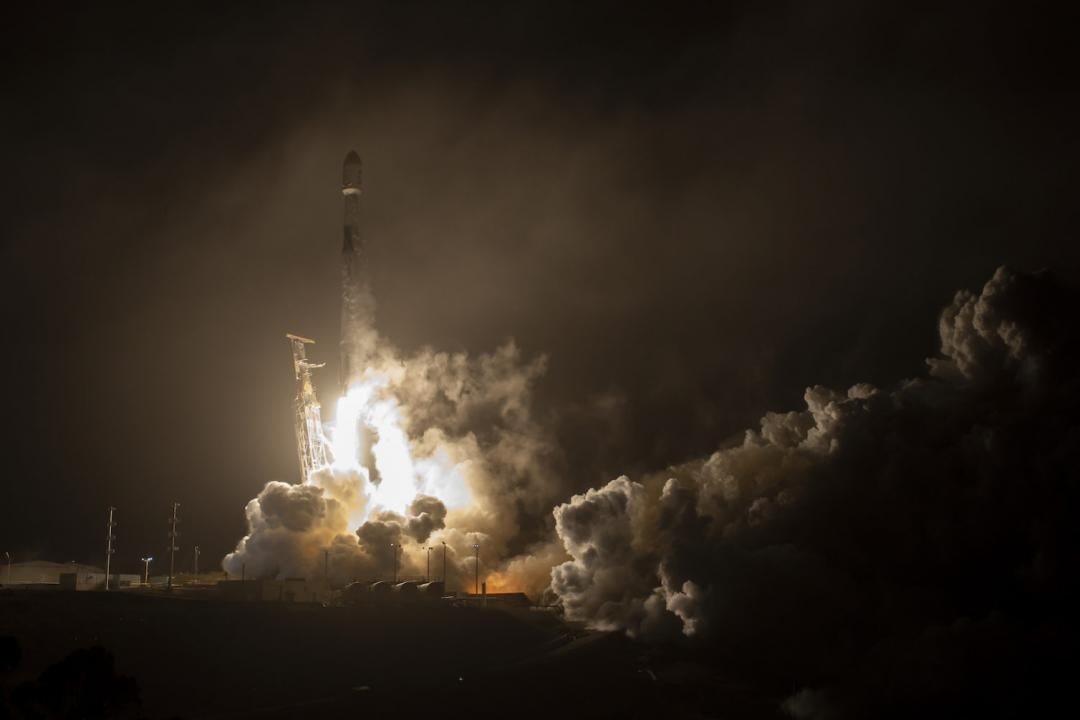 照片显示DART火箭在烟雾、火焰和昏暗的背景中发射