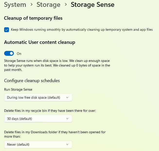 Windows Storage Sense settings page showing options for automatic cleanup of temporary files, with Storage Sense turned on and settings to run during low disk space, delete recycle bin files after 30 days and manage Downloads folder cleanup.