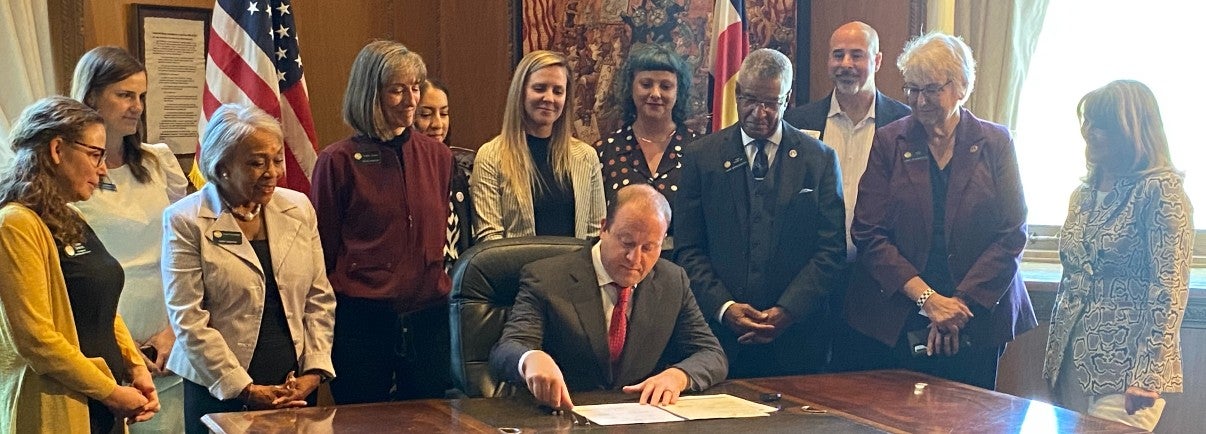 Regents Sue Sharkey & Ilana Spiegel, AVP of State Relations Heather Rezko with Senators Janet Buckner (D-Aurora) & Tammy Story (D-Conifer) and Reps Tony Exum Sr. (D-Colorado Springs) & Cathy Kipp (D-Ft. Collins) watch Gov. Polis sign bill HB21-1067