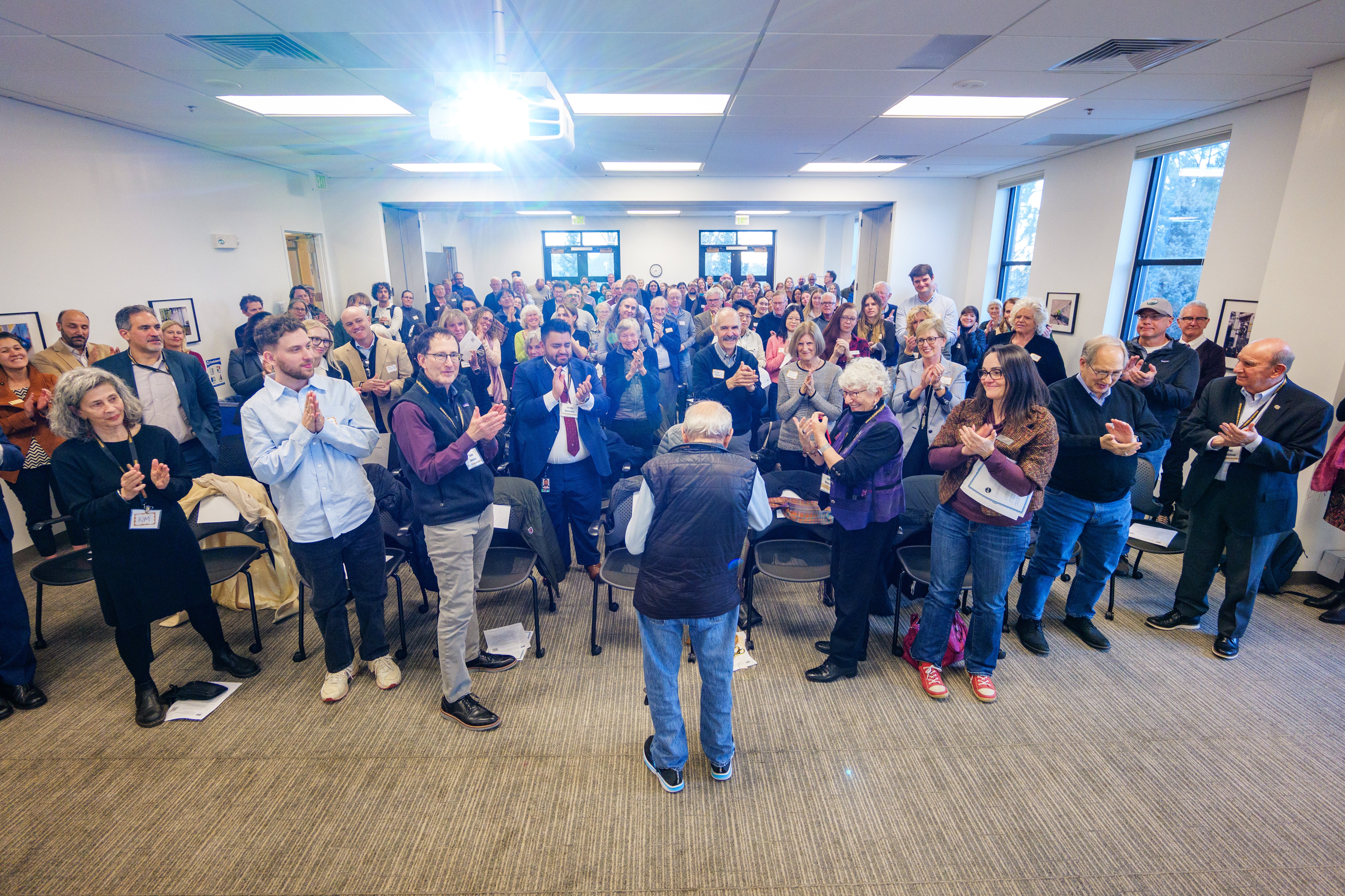 A group of people applauing Richard Jessor at the Richard Jessor Building ribbon cutting & IBS Open House