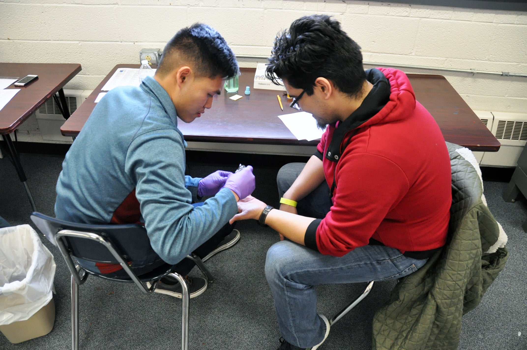 First year UUT M.D. student Minh Do, left, performs a glucose test on a patient at the health fair.