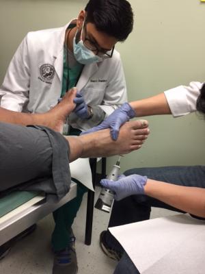 CU SOM student Shayer Chowdhury assists a client at the foot clinic