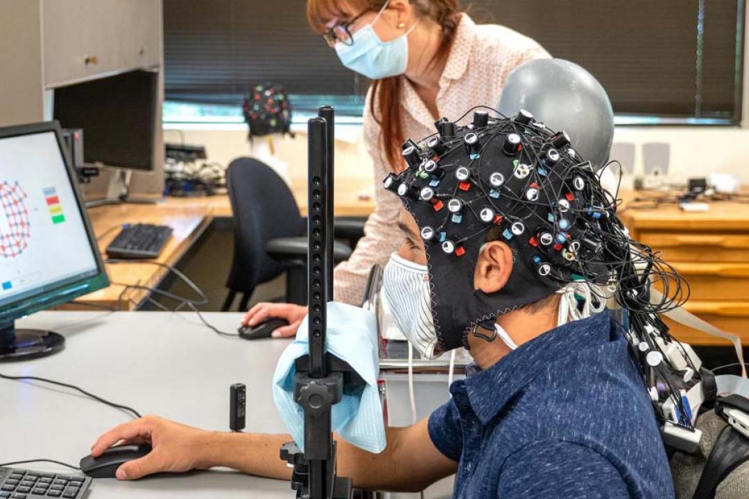 CU Boulder postdoctoral researcher Rosy Southwell and undergraduate student Cooper Steputis demonstrate a functional near-infrared spectroscopy device, which can monitor brain activity.
