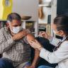 Photo of a doctor giving a patient a shot in their left arm.