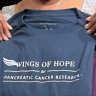 Photo of a woman's hands holding up a T-shirt that reads: "Wings of Hope for pancreatic cancer research."