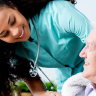 Stock photo of a healthcare provider leaning over the shoulder of an elderly patient.