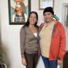 Violeta Chapin standing with Irma Bernard, a woman the clinic helped become a U.S. citizen. Chapin wearing a brown cardigan and pants. Bernard wearing a tan CU shirt and orange jacket. 