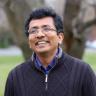 Professor Sriram Sankaranarayanan smiling in a black quarter zip sweater