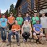 Mountain Research Center group photo outside on wood deck with wood cabin behind. 9 total members. 