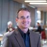 Keith Molenaar smiling for a picture wearing a brown suit jacket with a dark blue button up shirt