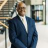 Dr. Lynn in a navy vlue suit with white shirt and yellow tie. 